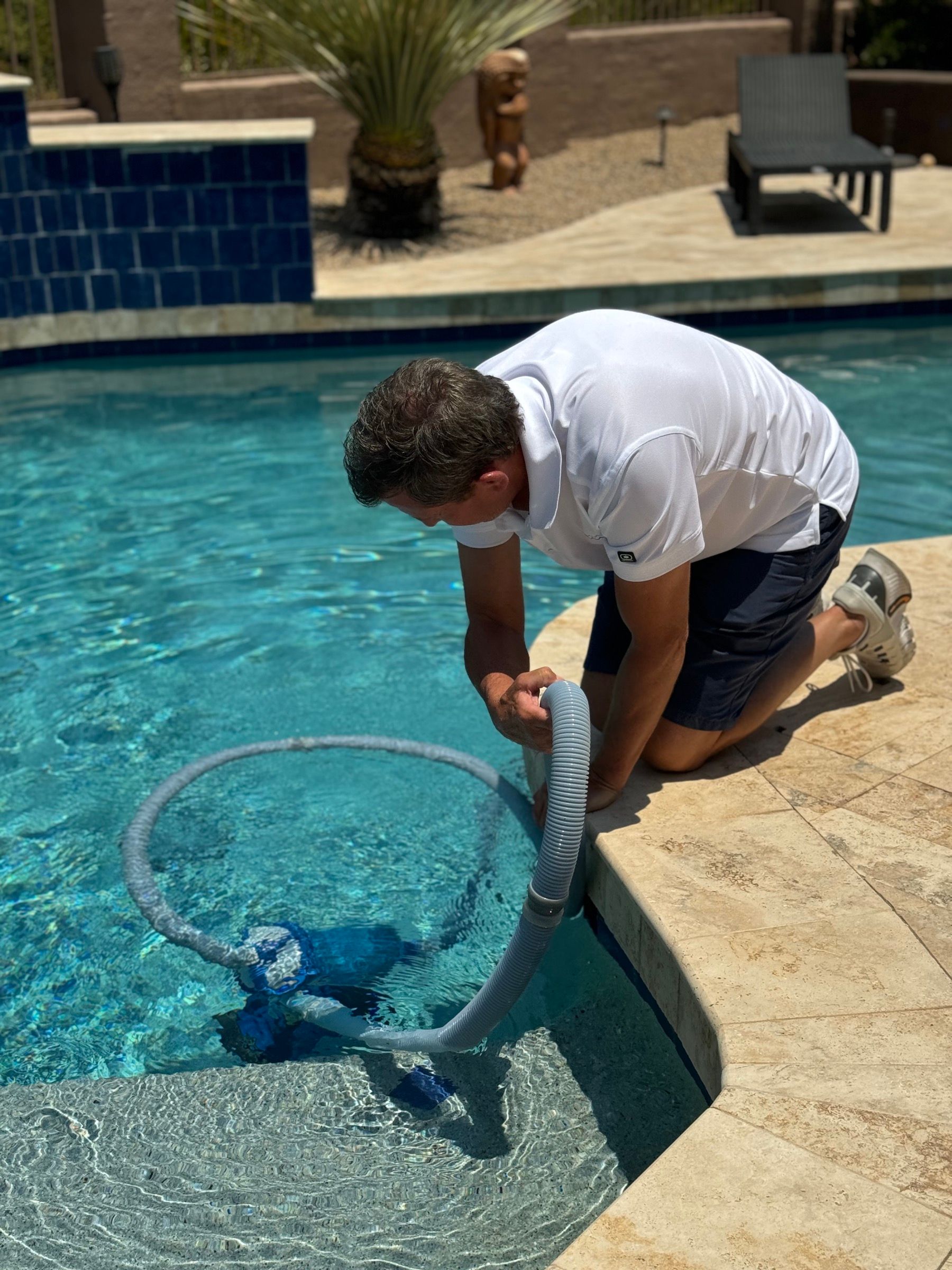 A Crystal Clear Pools technician vacuuming a backyard pool